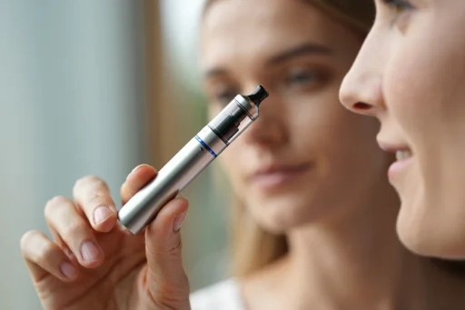 ego AIOのようなペン型ベイプデバイスを手に持ち、使い方を確認している様子。